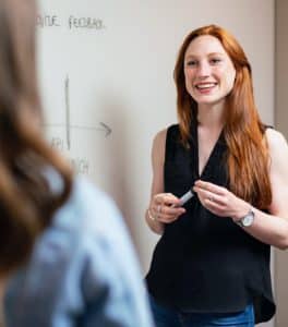 Woman with long red hair chatting to colleague