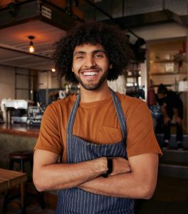 Young barista smiling in coffee shop
