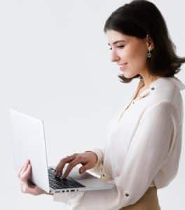 A Woman Typing on Laptop while Standing
